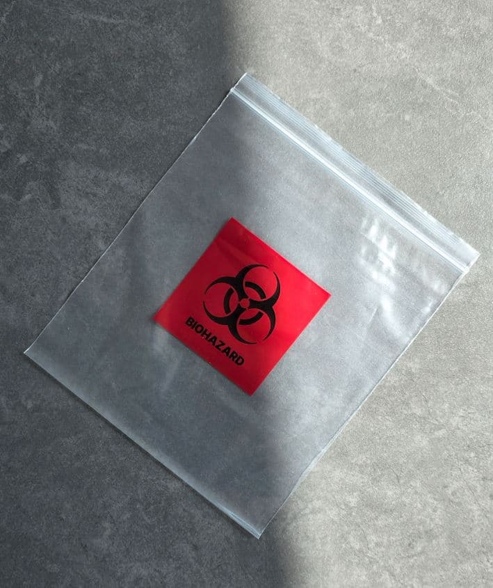 투명 지퍼백 가운데에 빨강 바탕과 검정 심볼로 BIOHAZARD 를 인쇄한 봉투